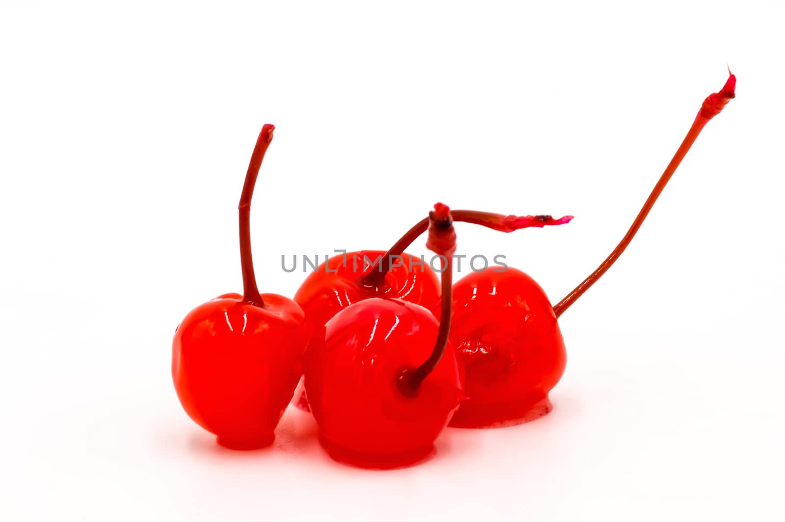 Group of four candied cherries with their stems on a white background