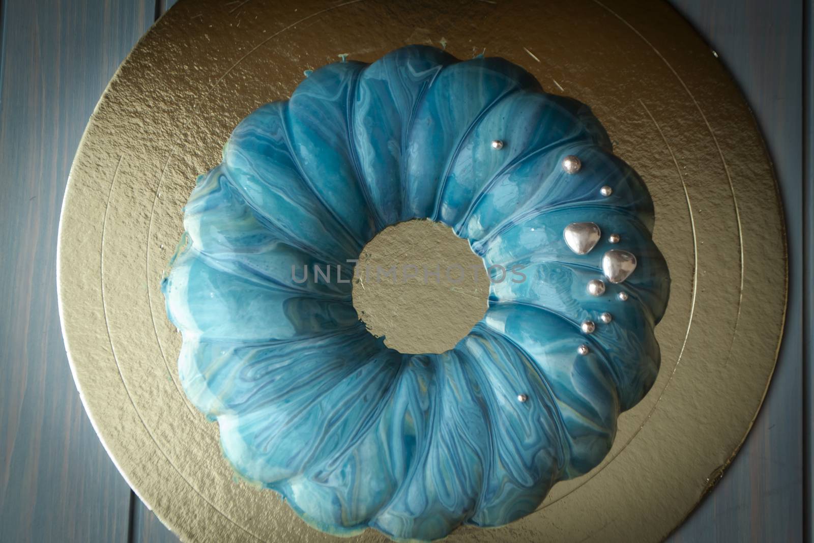 Modern french mousse cake with blue ocean mirror glaze and with silver decoration, top view