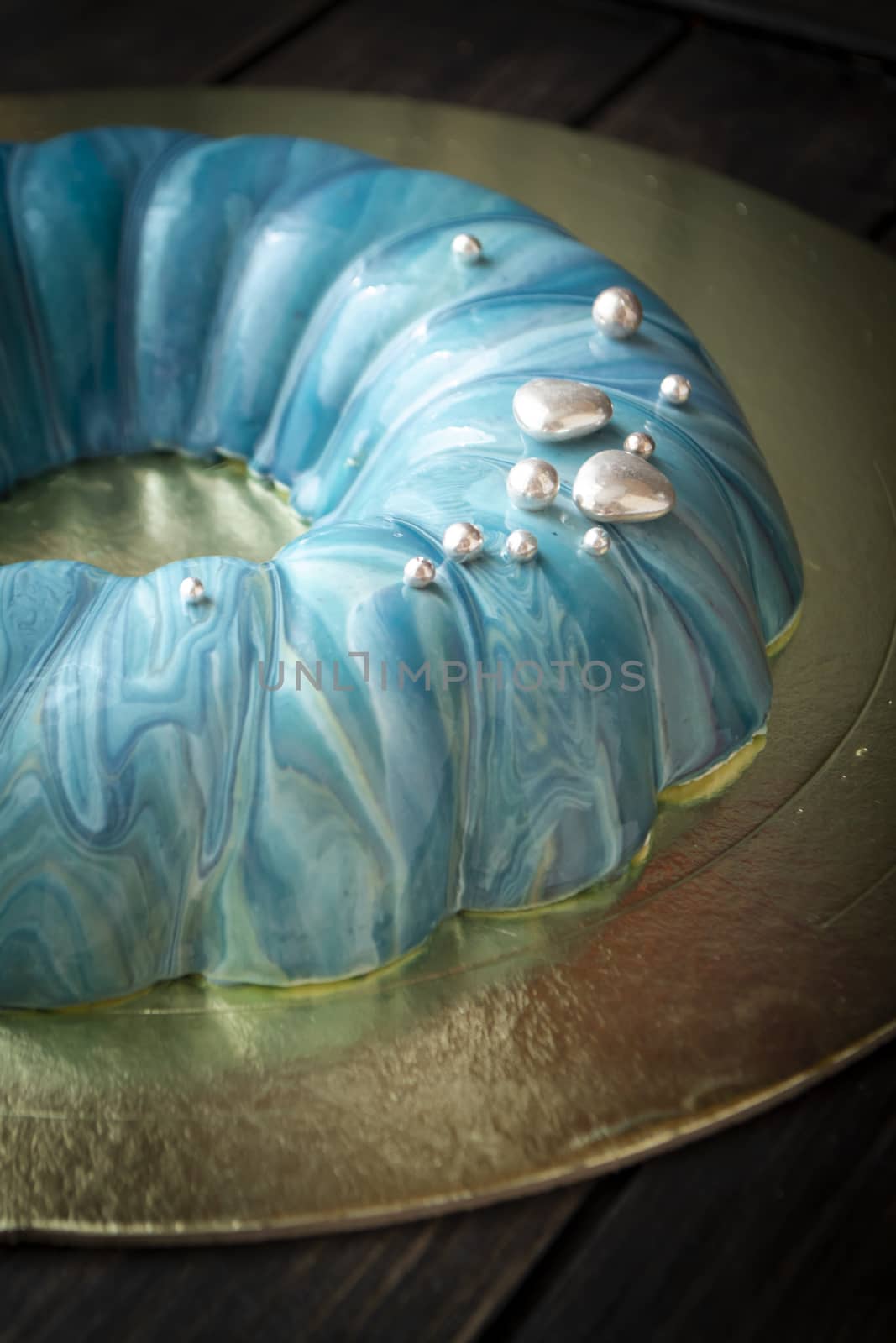 Mousse cake decorated in marine style covered with blue mirror glaze and silver decoration.