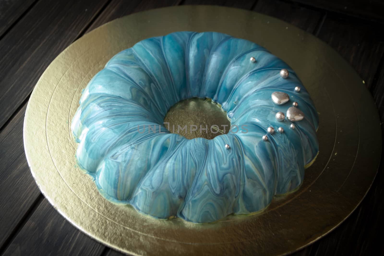 blue berry modern mousse cake, covered with a turquoise mirror glaze with sea effect.