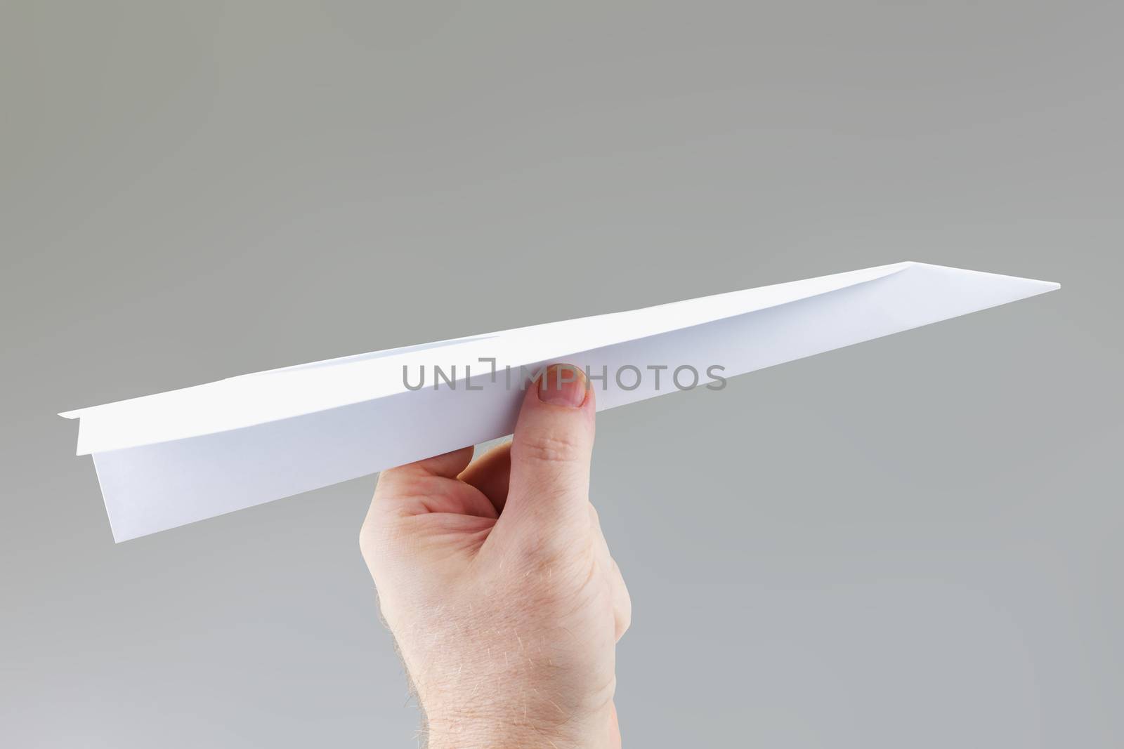A hand holding a paper dart plane ready to throw