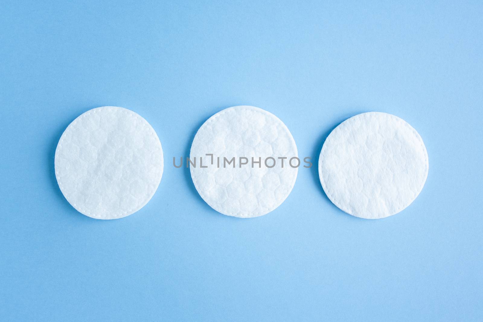 Organic cotton pads on blue background, cosmetics and make-up remover, hygiene and skincare. Close-Up Of Cotton Pads Over Blue Background