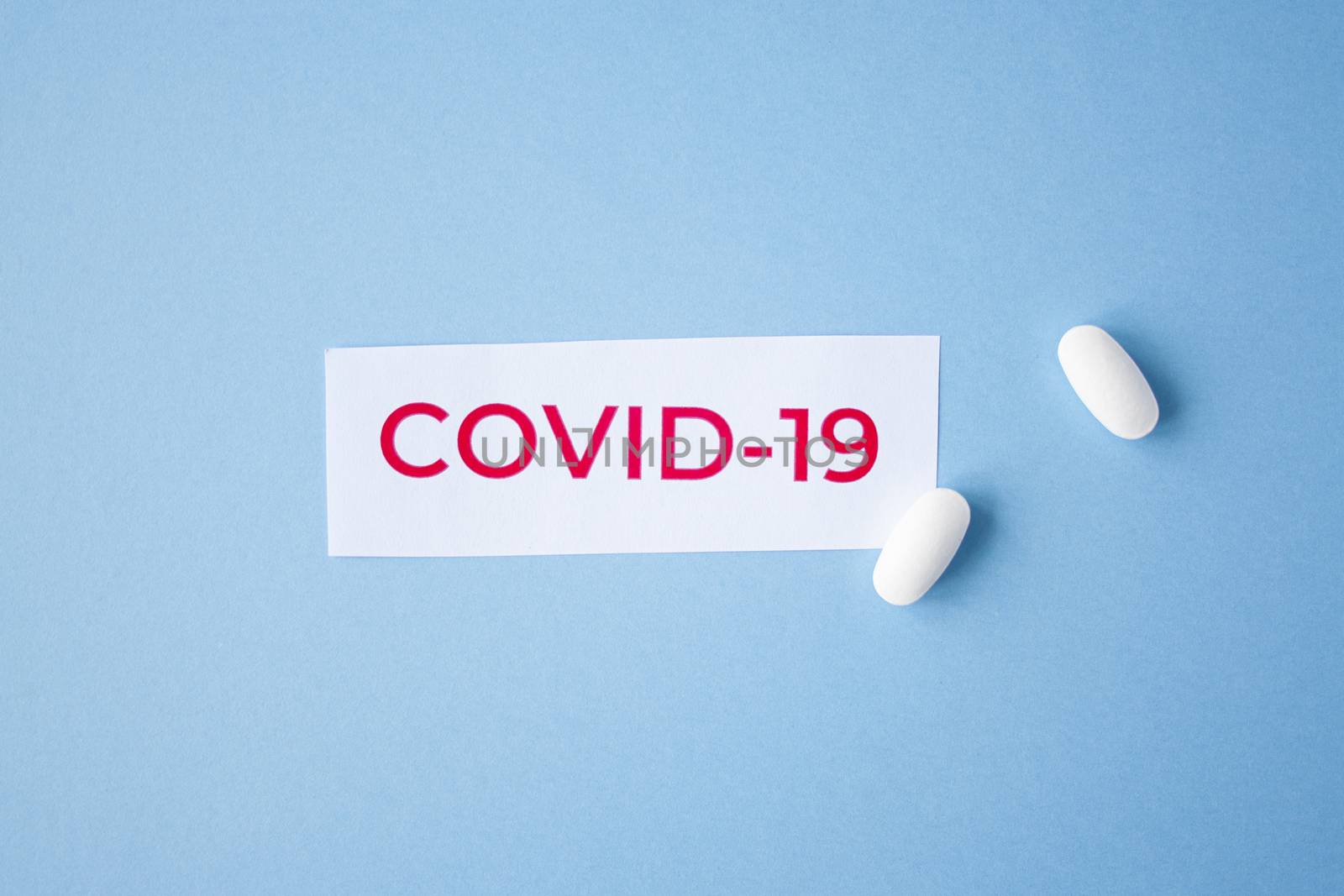 The inscription quote covid-19 on a blue background with two white tablets next to it. Coronavirus treatment concept. Medicines, vaccine for the virus.