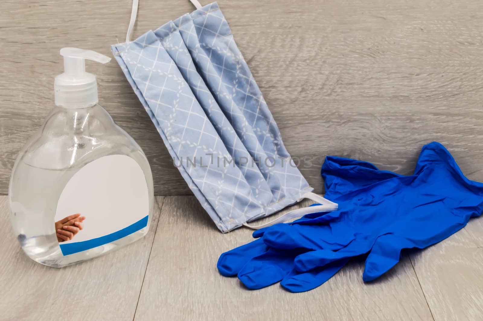 Hand sanitizing gel with a tissue mask and gloves for the prevention of coronavirus on a gray wooden background