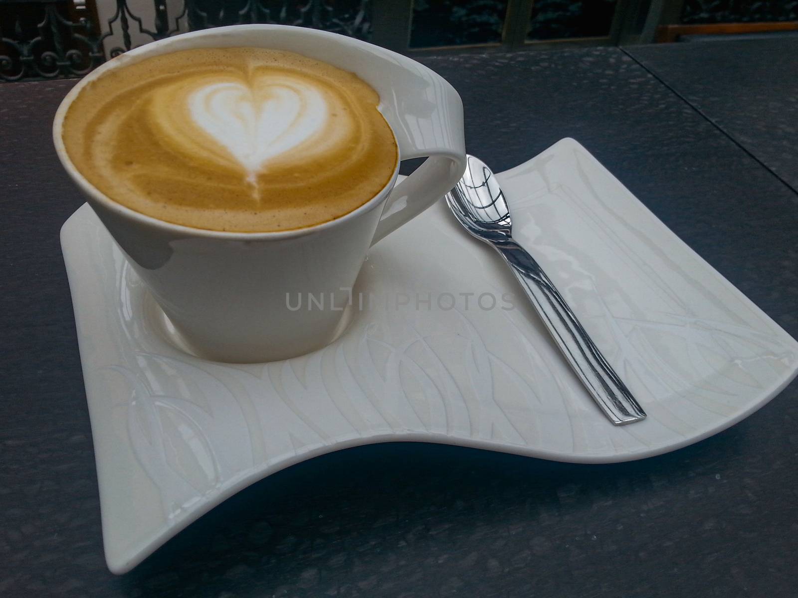 Cafe latte with heart latte art in cup on stand