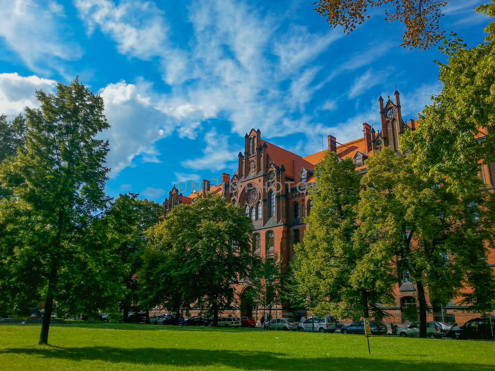 Angled look to cathedral buildings in front of small green park in Wroclaw City at sunny cloudy day by Wierzchu