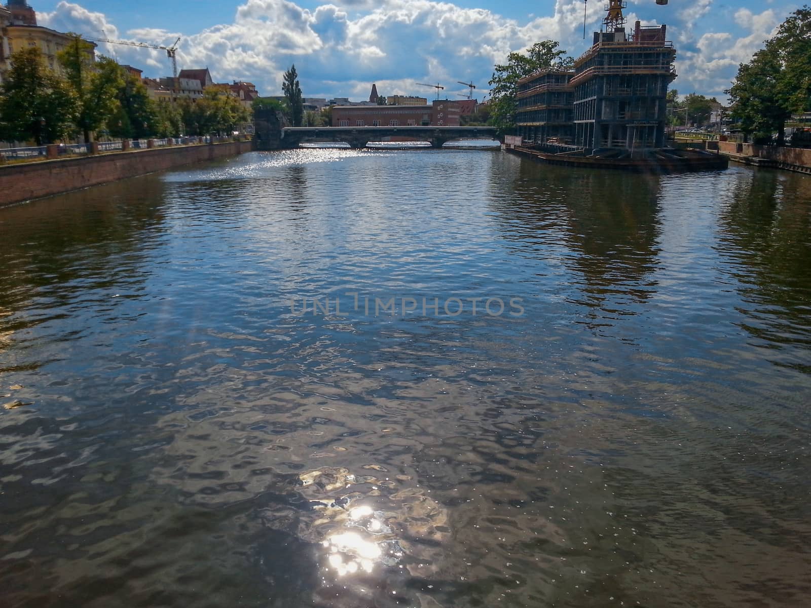 Sun reflecting in river in Wroclaw with city in background by Wierzchu