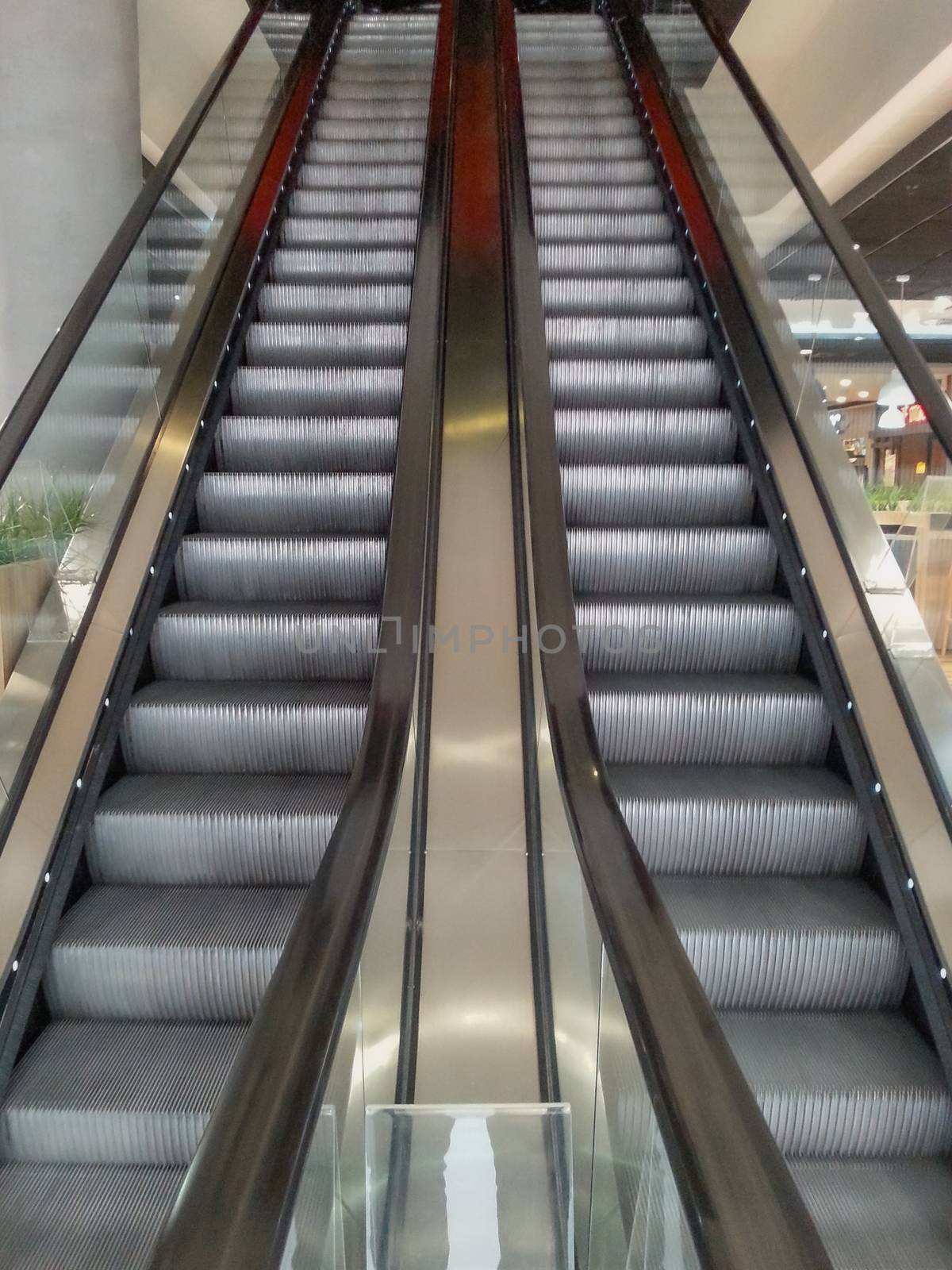 Symmetric escalator to darkness inside shopping mall by Wierzchu