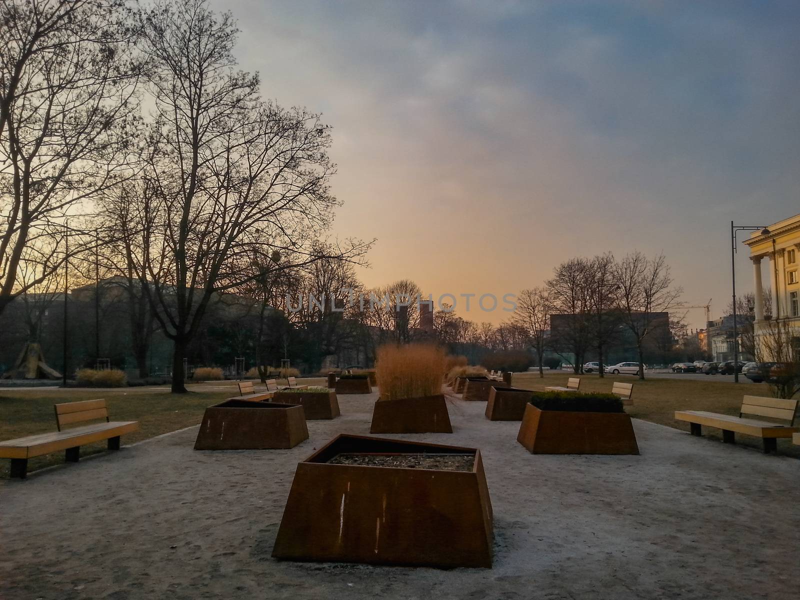 Huge flowerpots and benches around in boulevard at sunset in Wroclaw by Wierzchu