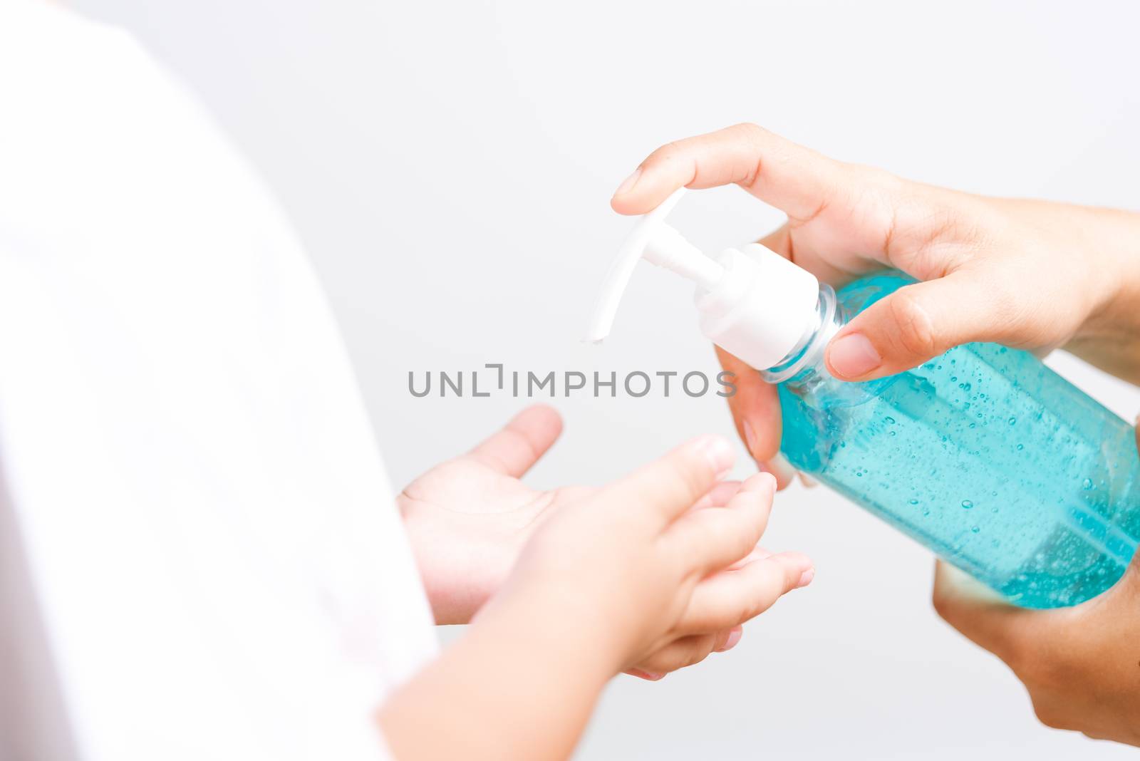 Closeup Asian Mother applying bottle pump dispenser sanitizer alcohol gel cleaning washing hands little child boy COVID-19 or coronavirus protection concept, isolated white background with copy space