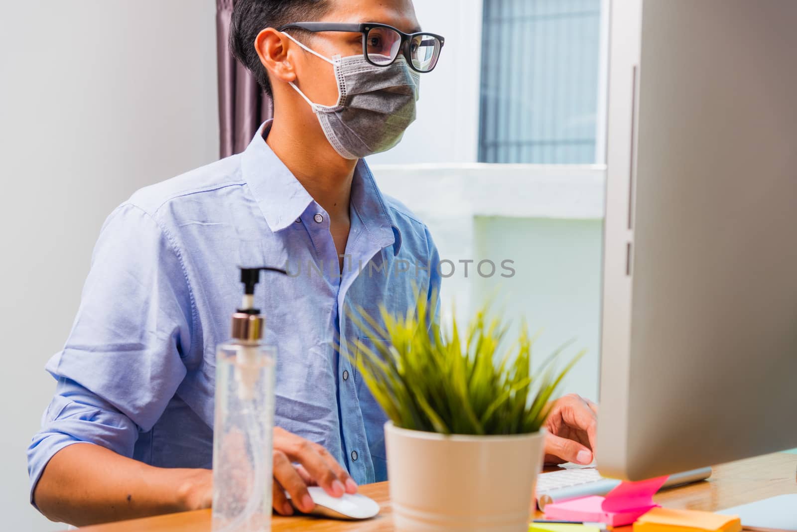 young man wearing a protective mask with disinfectant gel beside by Sorapop