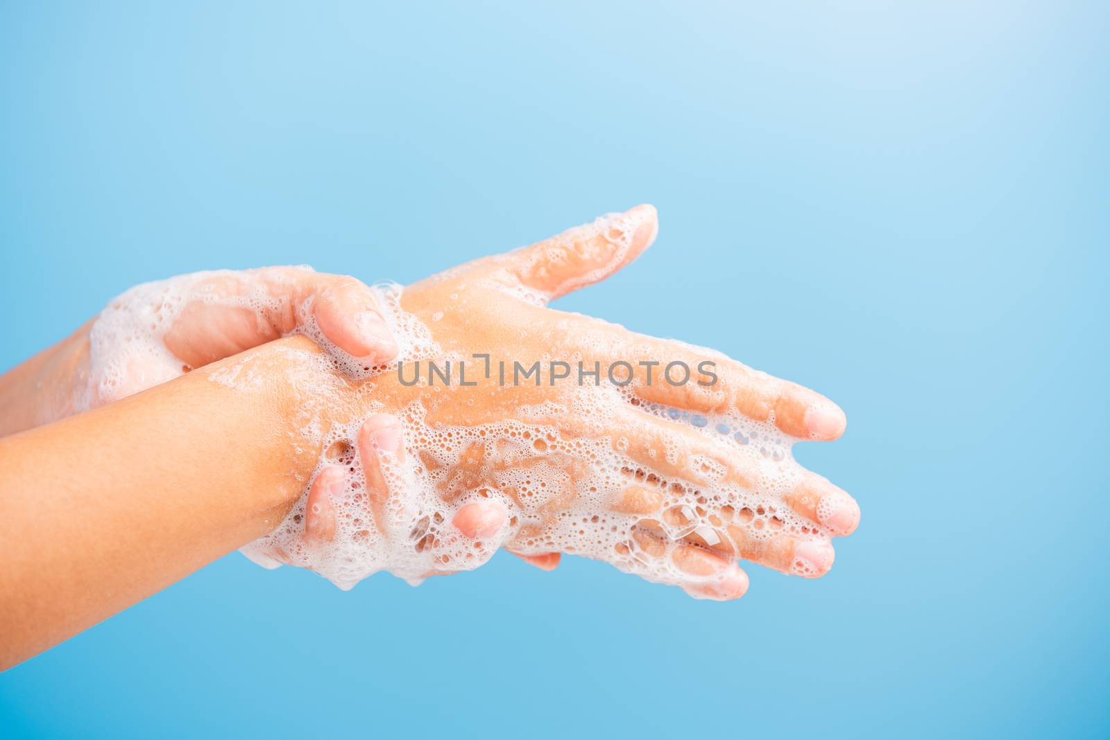Closeup body care Asian young woman washing hands with soap have foam, hygiene prevention COVID-19 or coronavirus protection concept, isolated on blue background