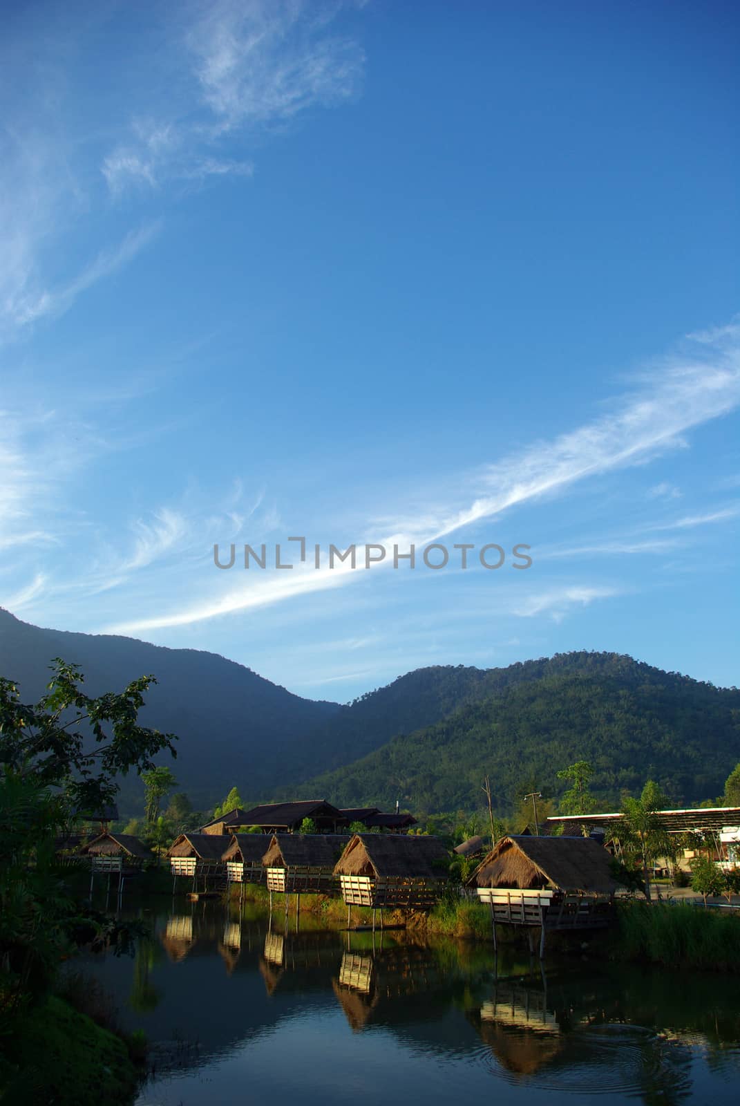 In the morning light small huts beside the lake and the mountain by Satakorn