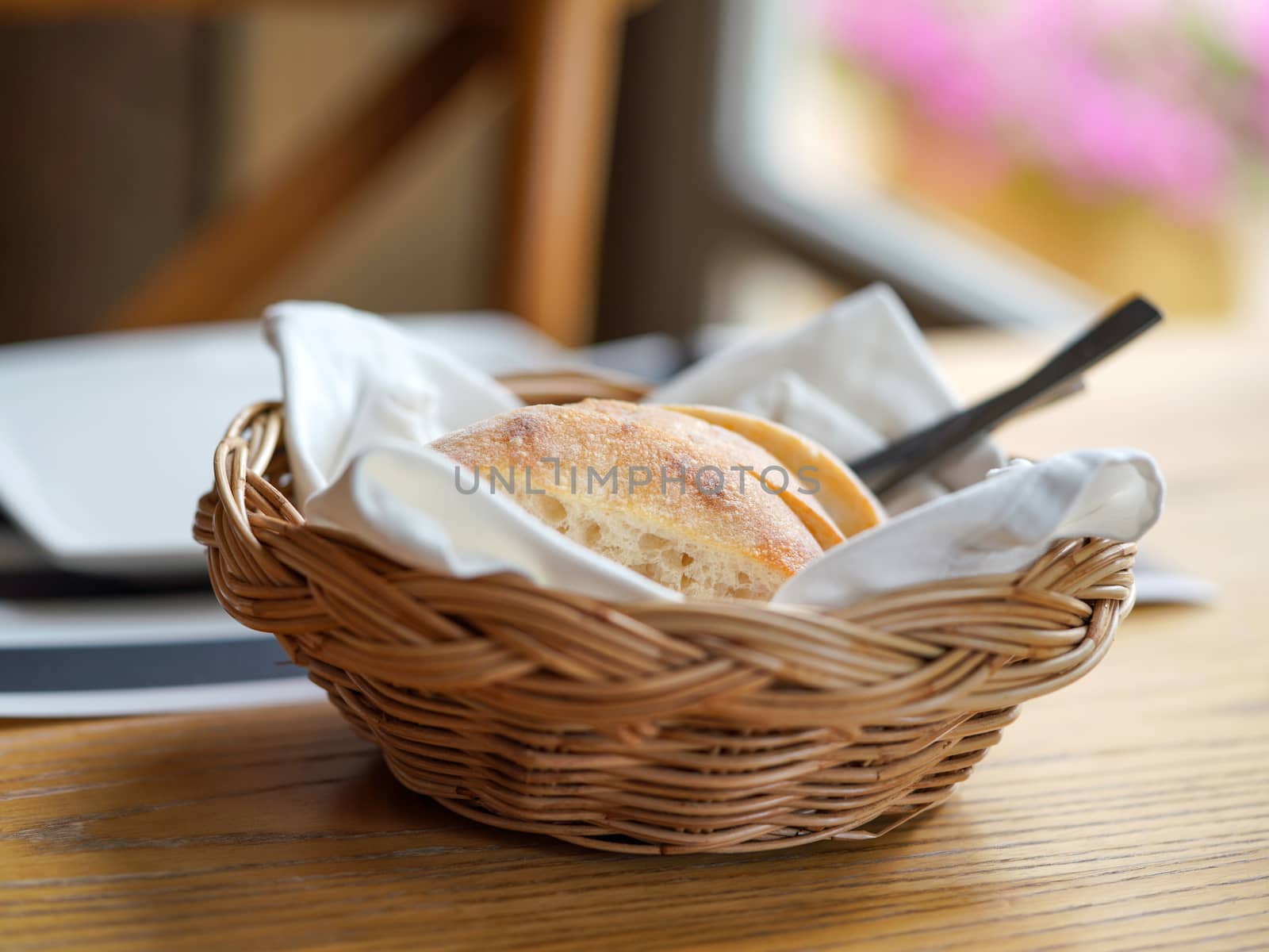 French bread sliced ​​in a basket on a wooden table near the window.