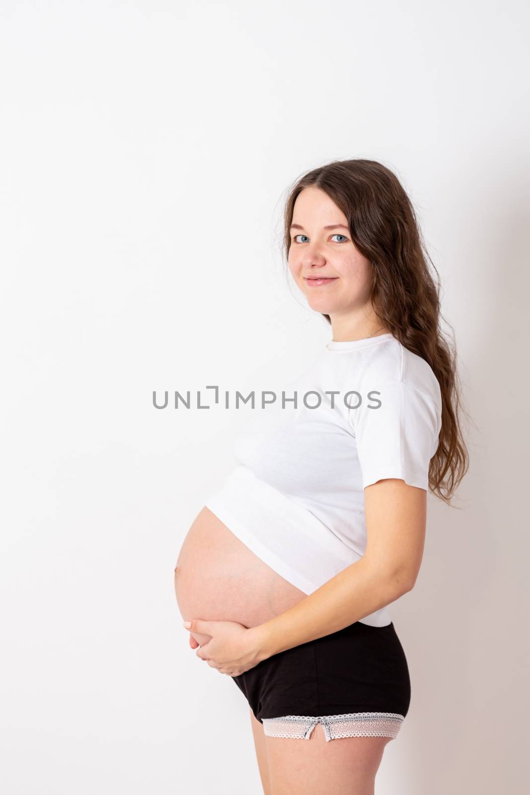 The young beautiful pregnant woman experiences strong emotions on a white background.