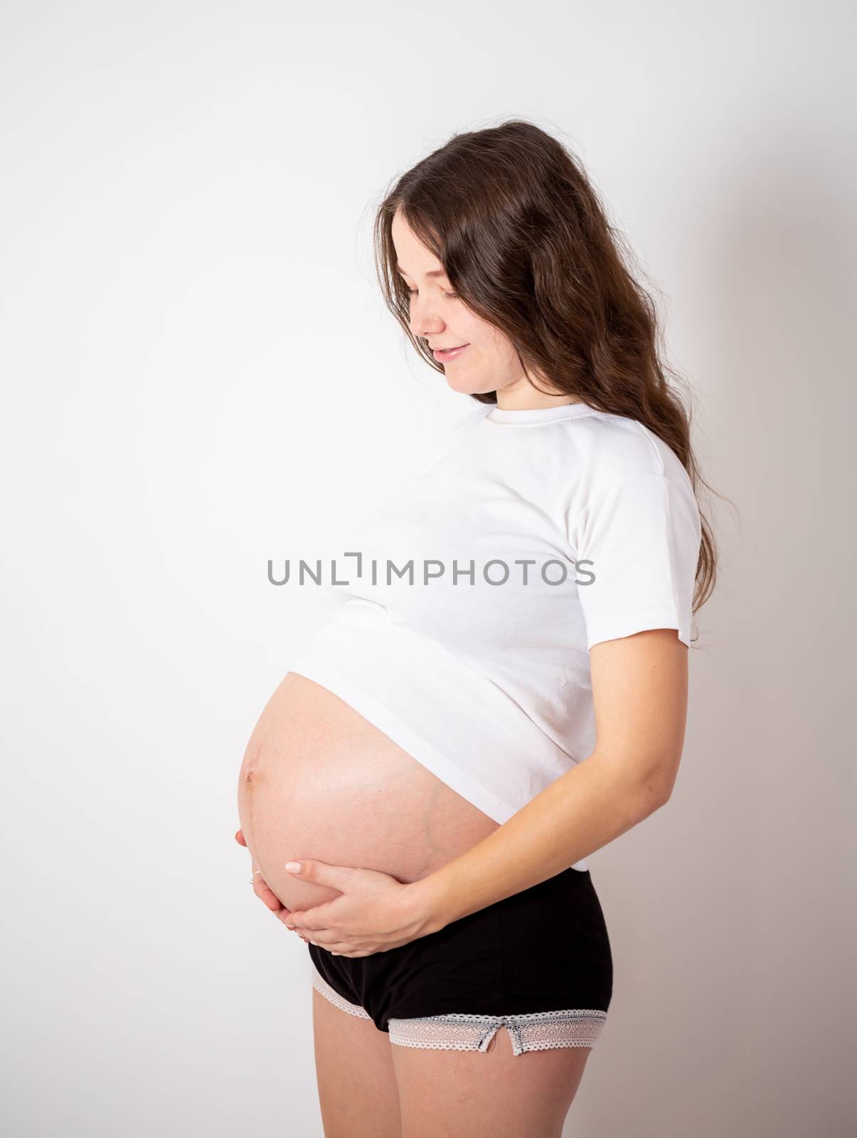 The young beautiful pregnant woman experiences strong emotions on a white background.