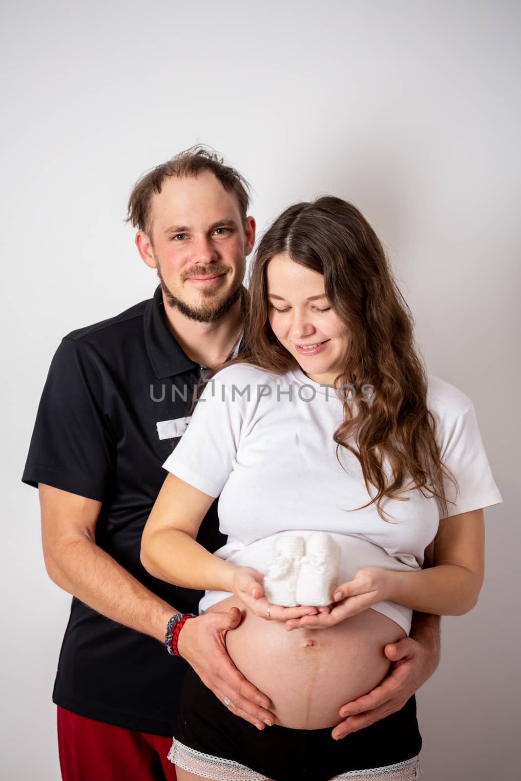 Cropped image of beautiful pregnant woman and her handsome husband hugging the tummy by Vassiliy
