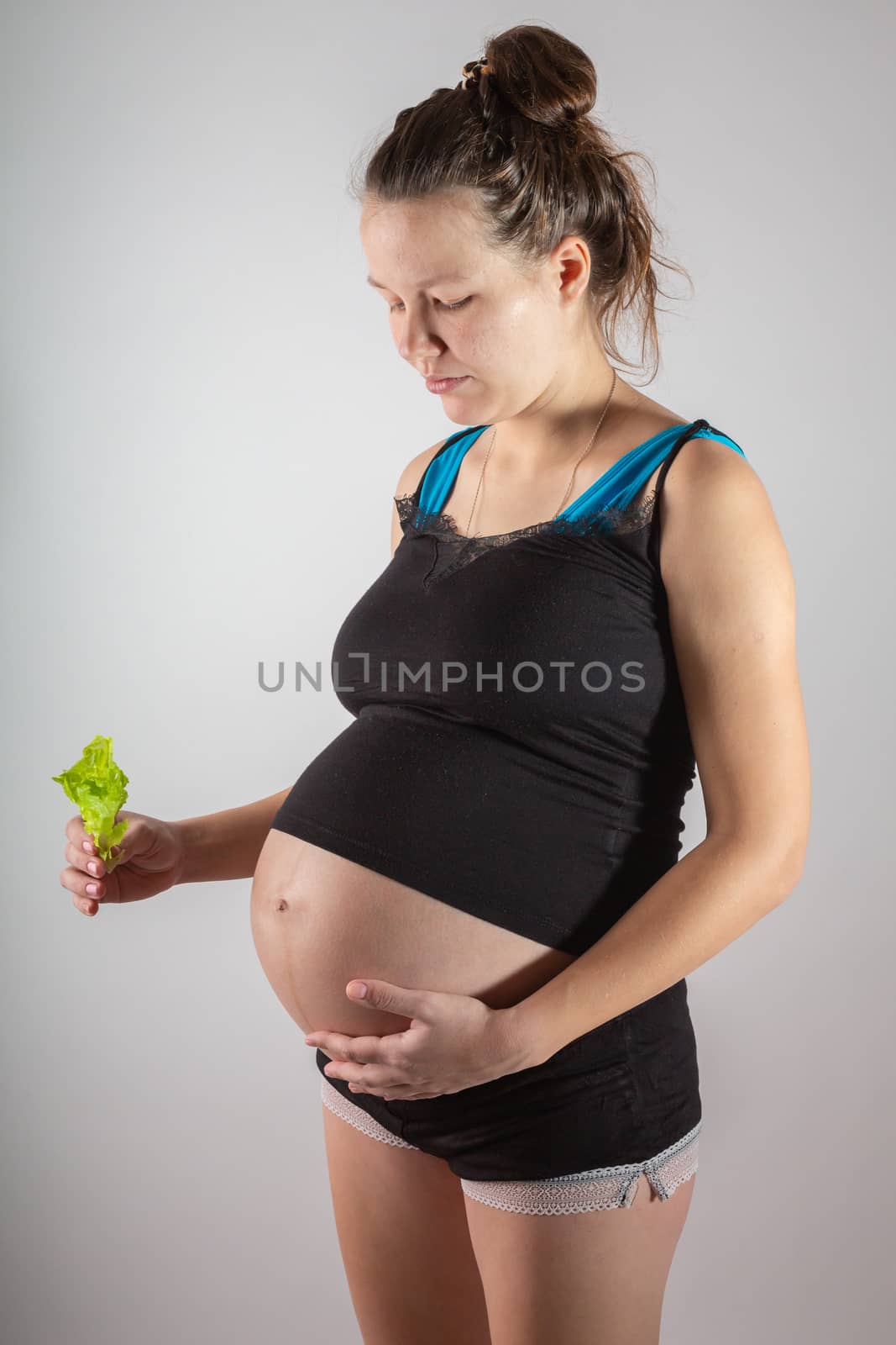 Pregnant woman holding glass bowl with fresh salad