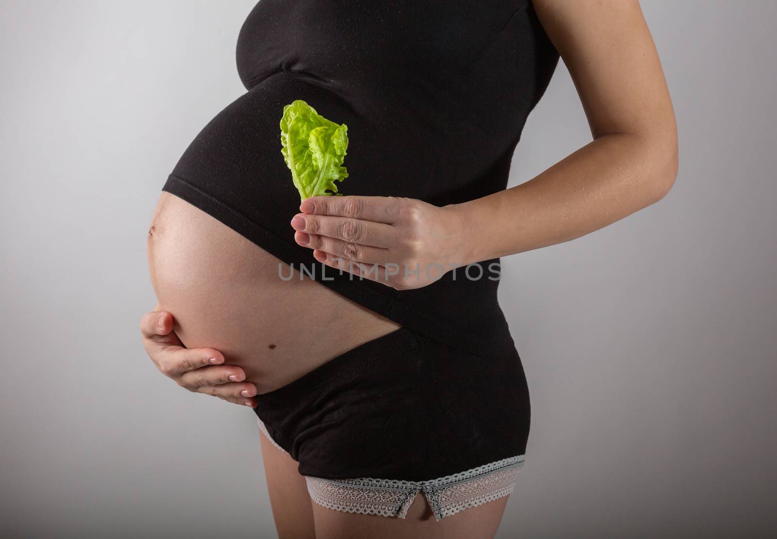 Pregnant woman holding glass bowl with fresh salad