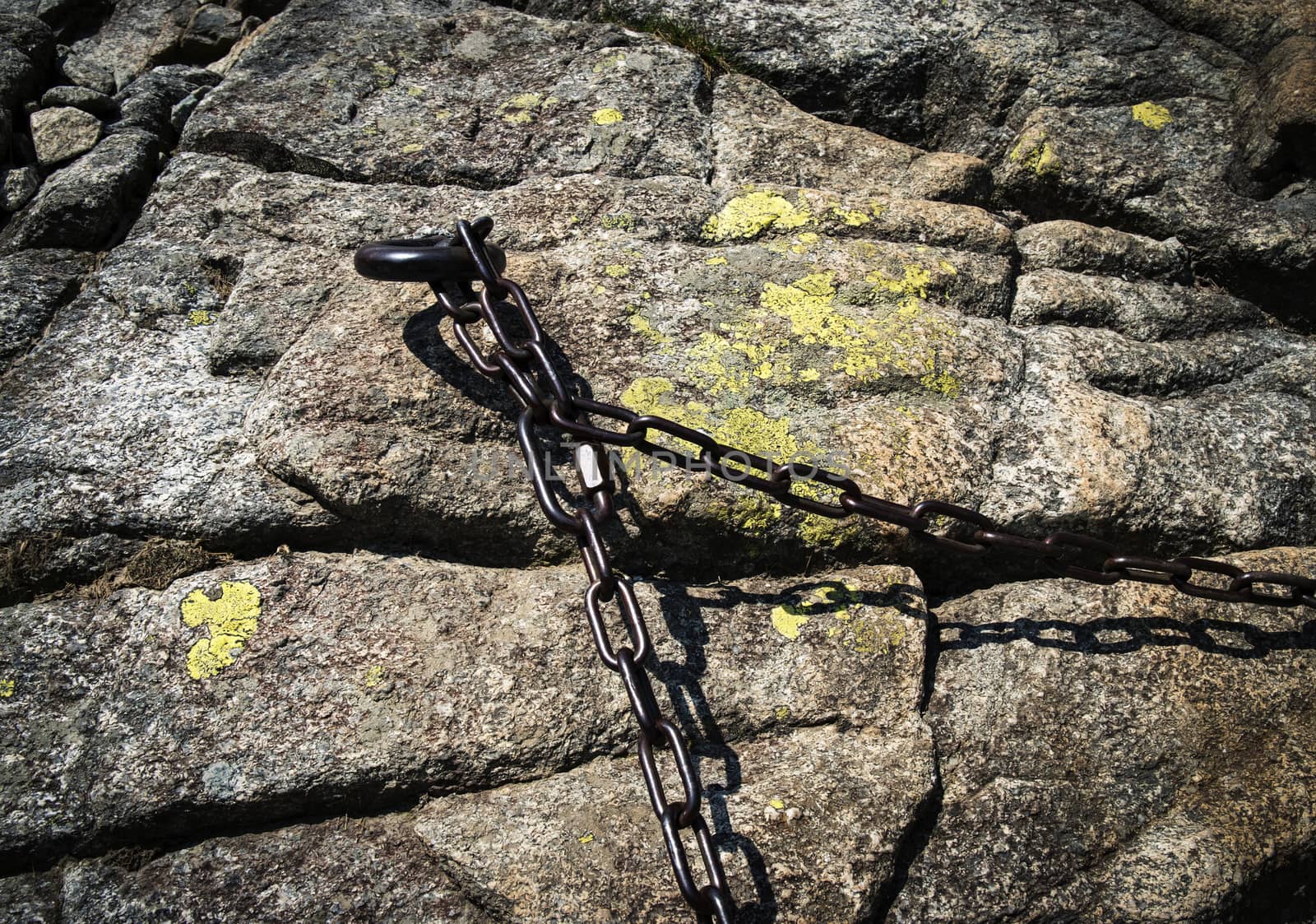 a rusty iron chain on a granite rock by Ahojdoma