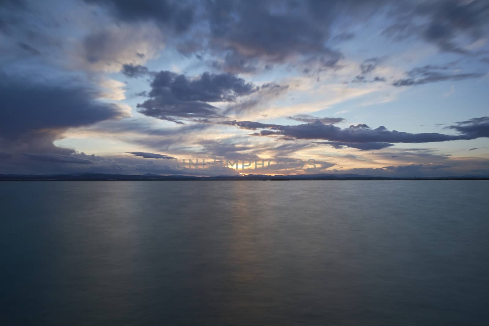 Landscape of a lake with storm clouds, moving waters reeds in the water, bluish tones, long exposure, silk effect