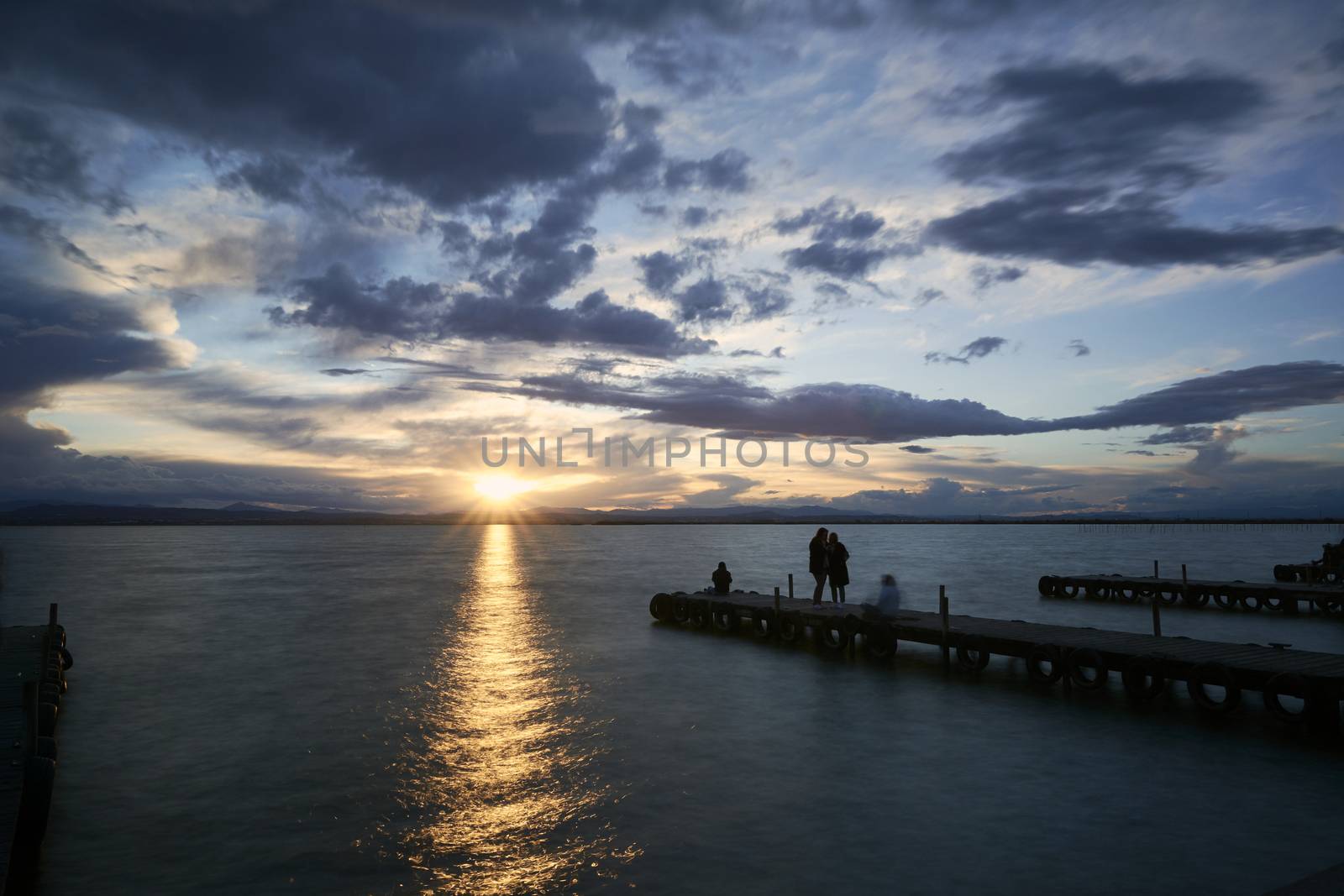 Landscape of a lake with storm clouds, moving waters reeds in the water, bluish tones, pier, long exposure, silk effect