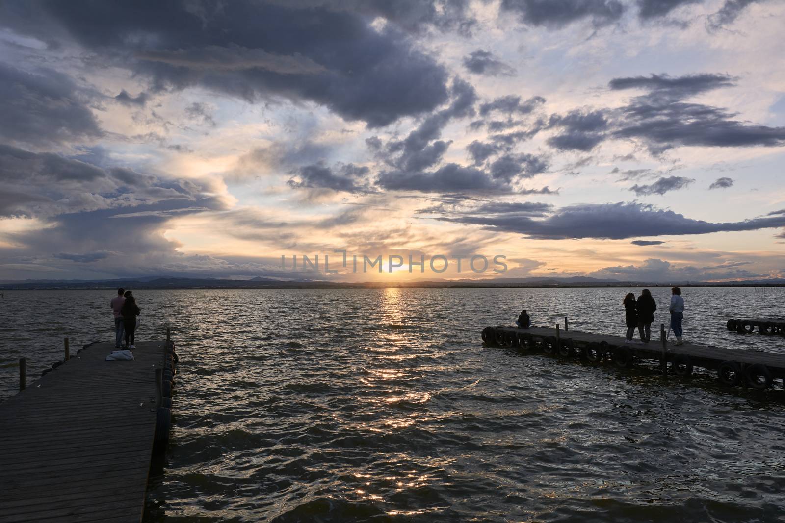 Landscape of a lake with storm clouds, moving waters reeds in the water, bluish tones, pier,