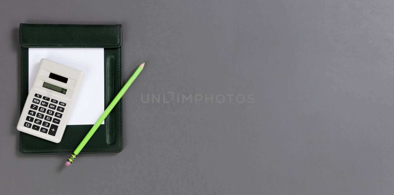Small calculator with paper and pencil on a gray table top with  by tab1962
