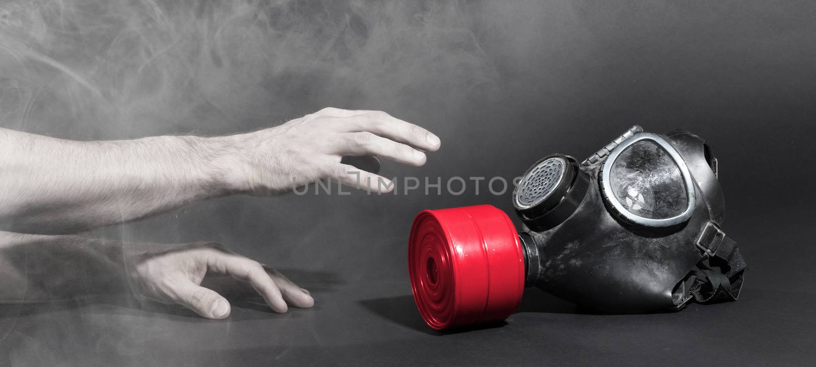 Man in room filled with smoke, trying to reach for vintage gasmask - Isolated on black - Red filter