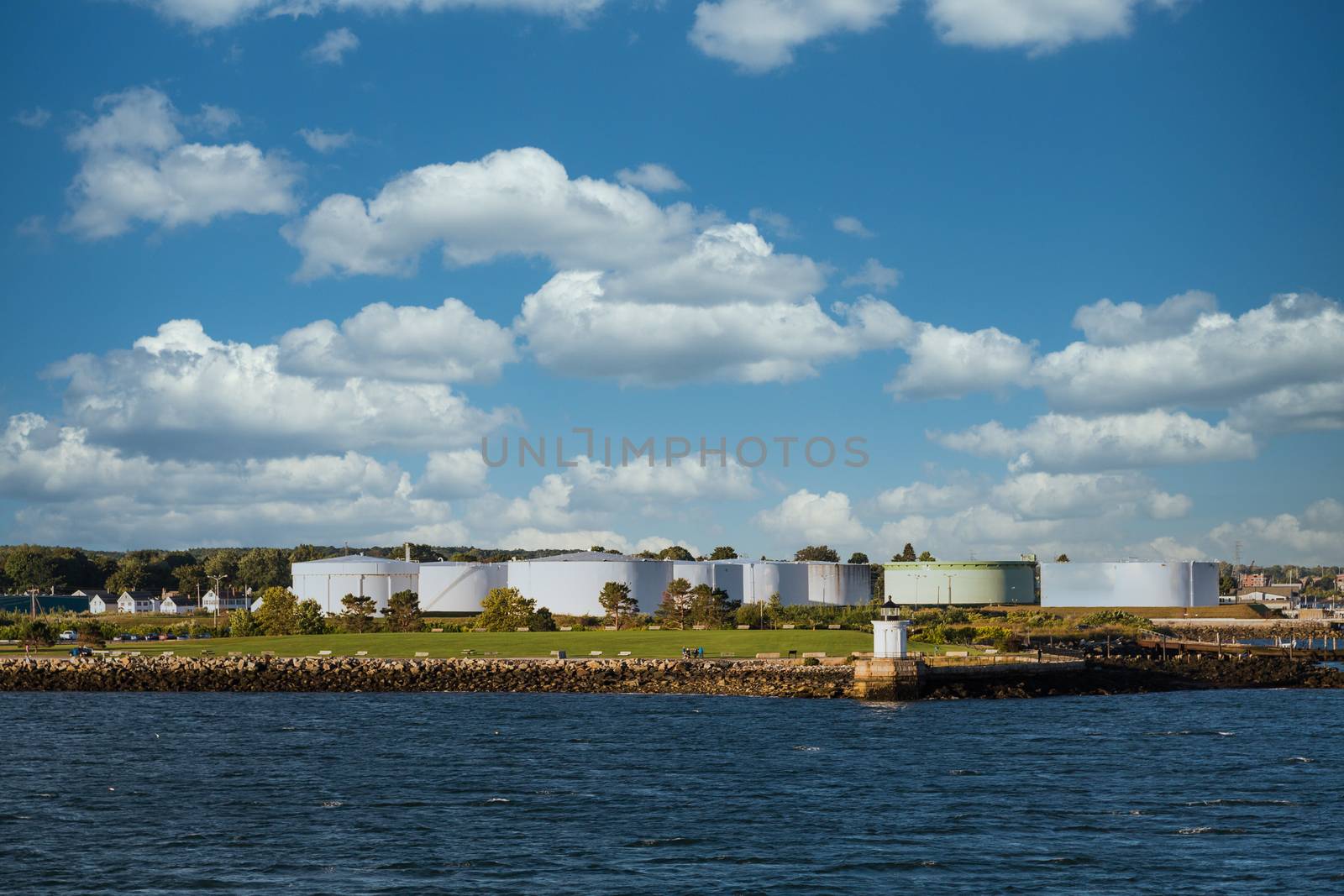 White Fuel tanks on the Canadian coast with a small lighthouse by the water