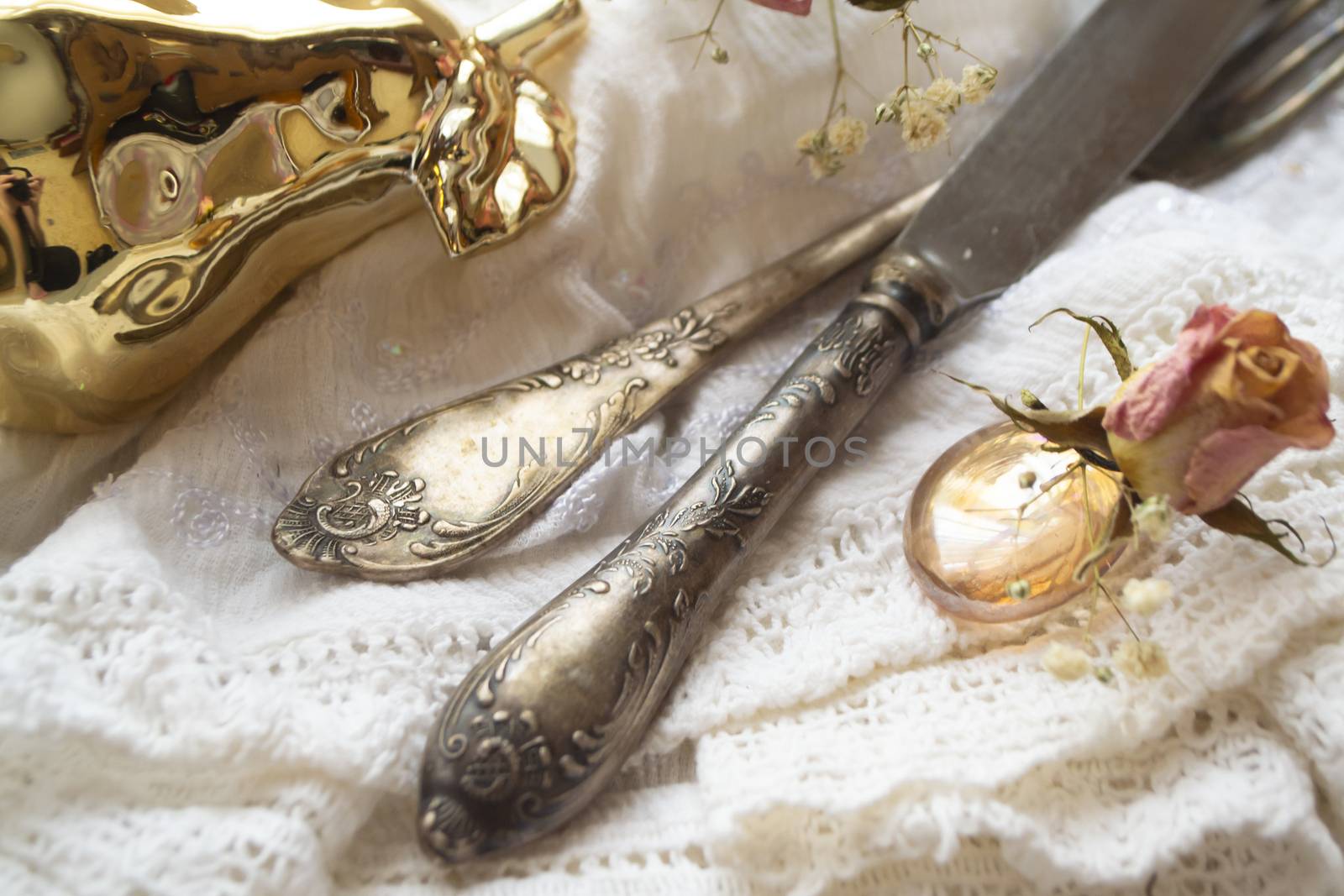 Romantic table setting. vintage fork and knife, napkin and pink dry roses on rustic wooden background