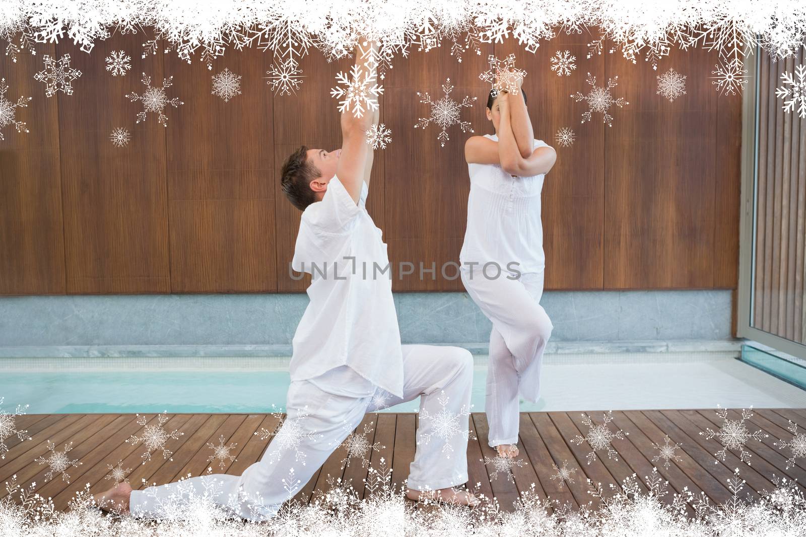 Peaceful couple in white doing yoga together against fir tree forest and snowflakes