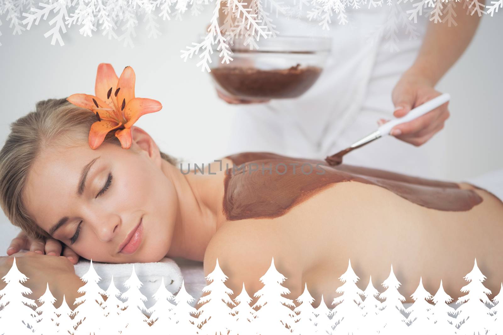 Beautiful blonde enjoying a chocolate beauty treatment  against fir tree forest and snowflakes