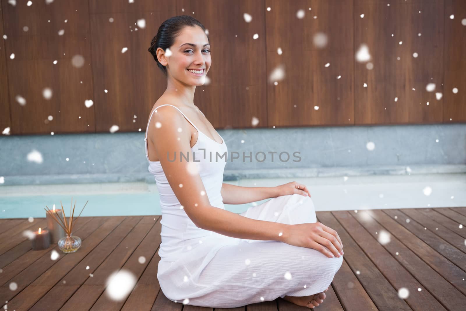 Content brunette in white sitting in lotus pose  against snow falling