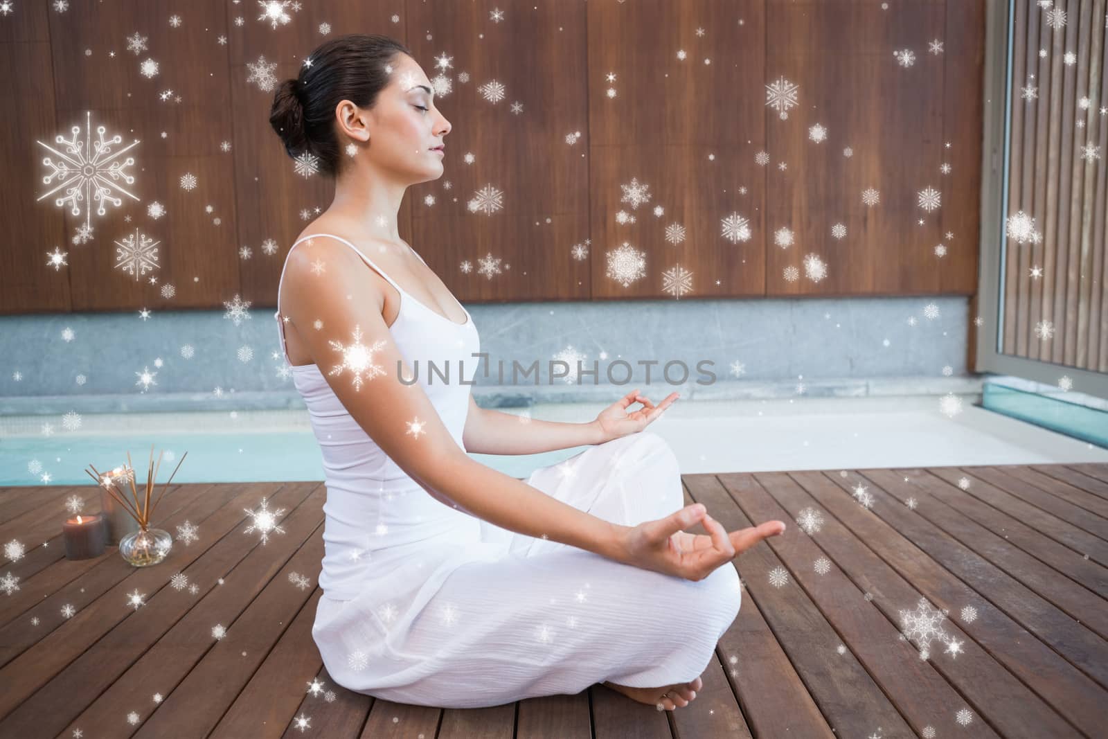 Peaceful brunette in white sitting in lotus pose  against snow falling