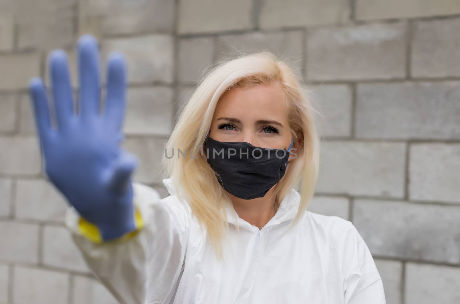 Woman in mask, white protective suit and gloves making sigh stop by Angel_a