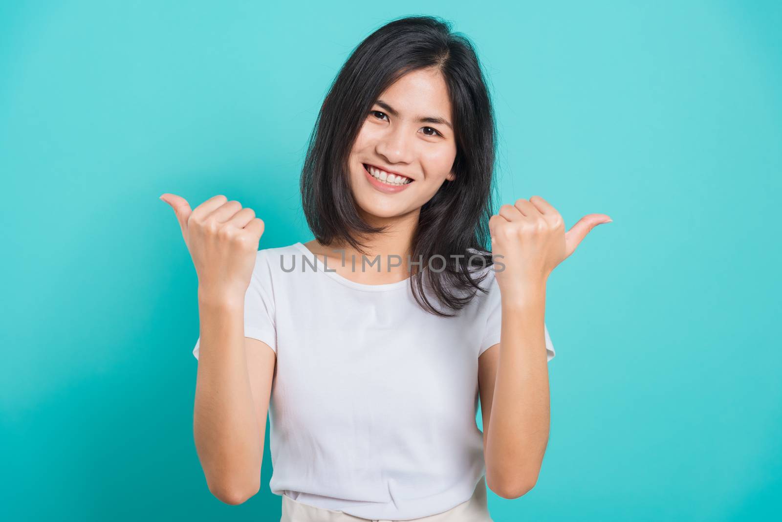 Portrait Asian beautiful happy young woman smile white teeth wear white t-shirt standing successful woman giving two thumbs up gesture, on a blue background with copy space