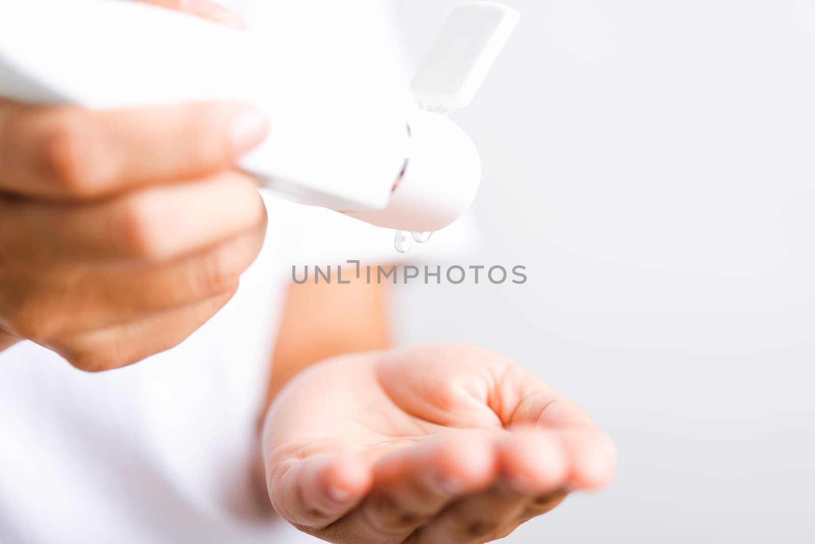 young woman applying drop dispenser sanitizer alcohol gel on han by Sorapop