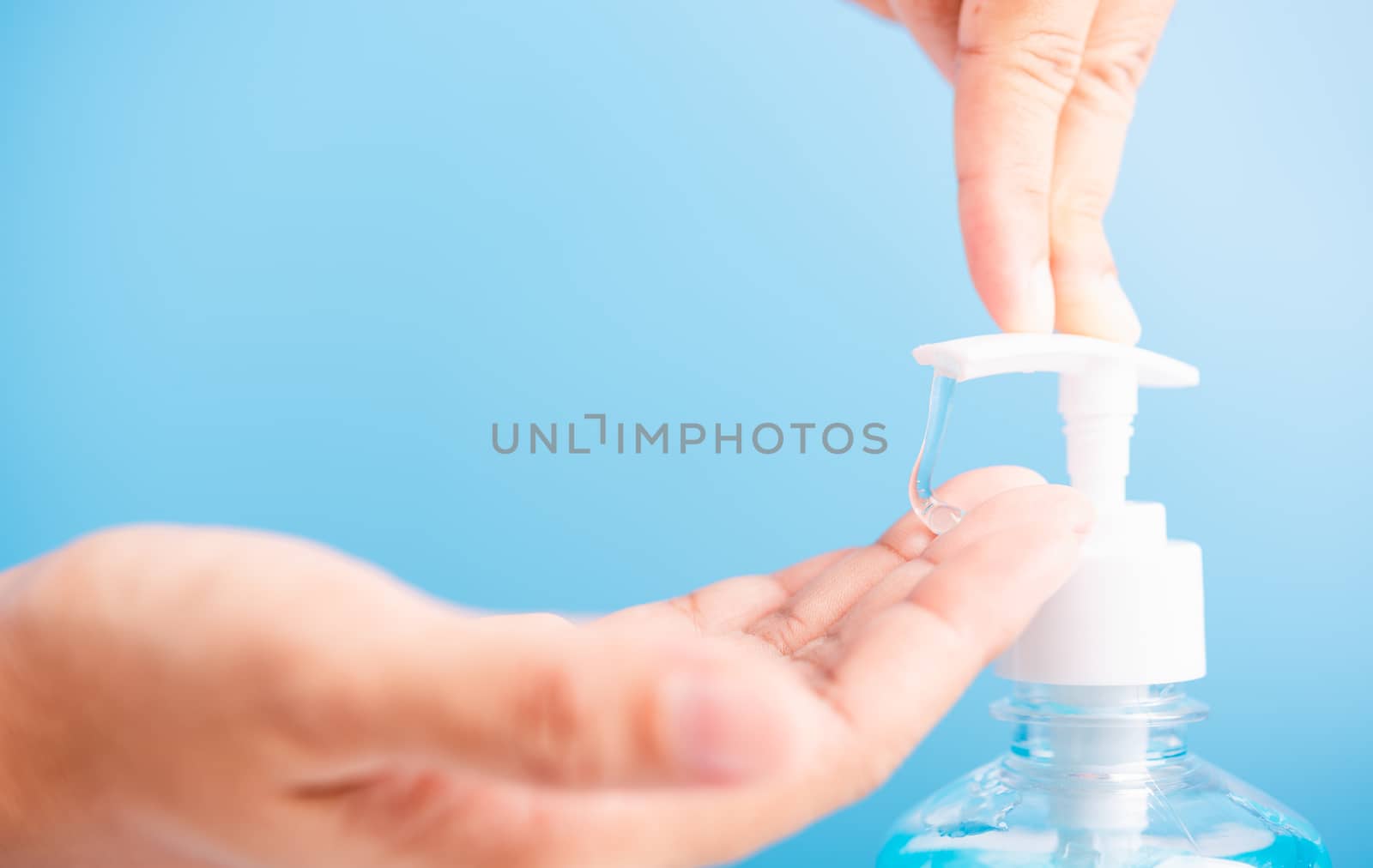 Close up Asian young woman applying press dispenser sanitizer alcohol gel pump to hand wash cleaning, hygiene prevention COVID-19 or coronavirus protection concept, isolated on blue background