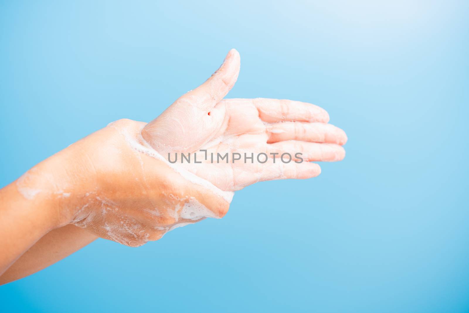 Closeup body care Asian young woman washing hands with soap have foam, hygiene prevention COVID-19 or coronavirus protection concept, isolated on blue background