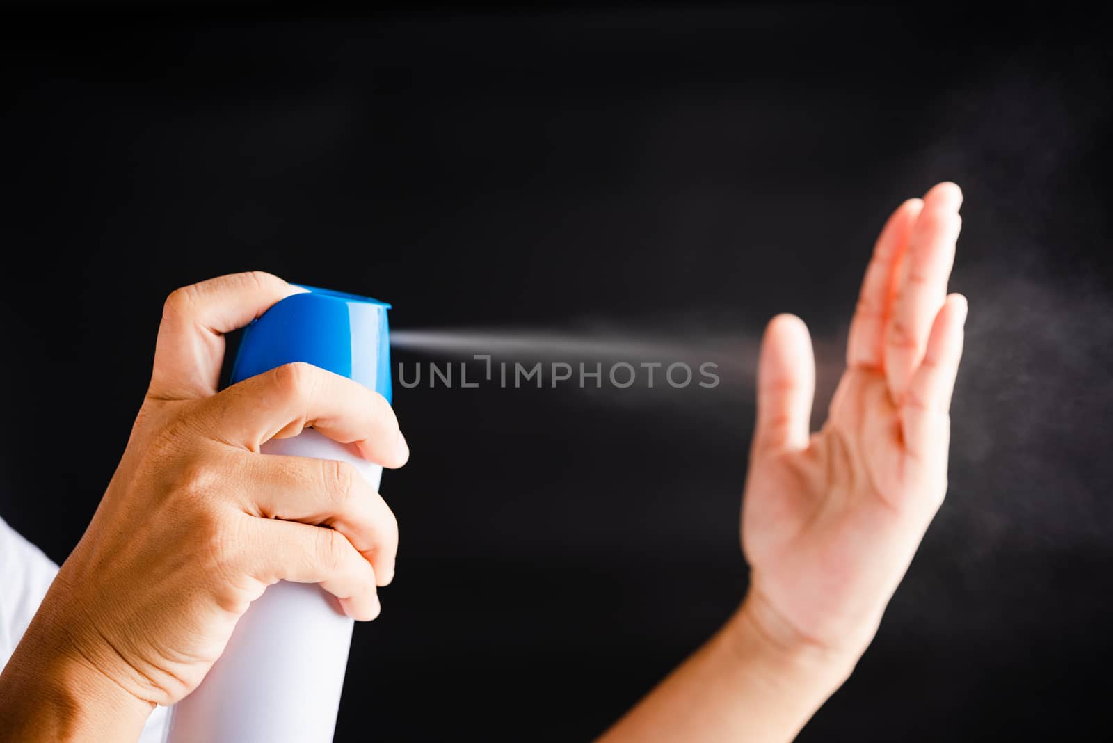 Closeup Hand Asian young woman applying spray pump dispenser sanitizer alcohol on hand wash cleaning, hygiene prevention COVID-19 or coronavirus protection concept, isolated on black background