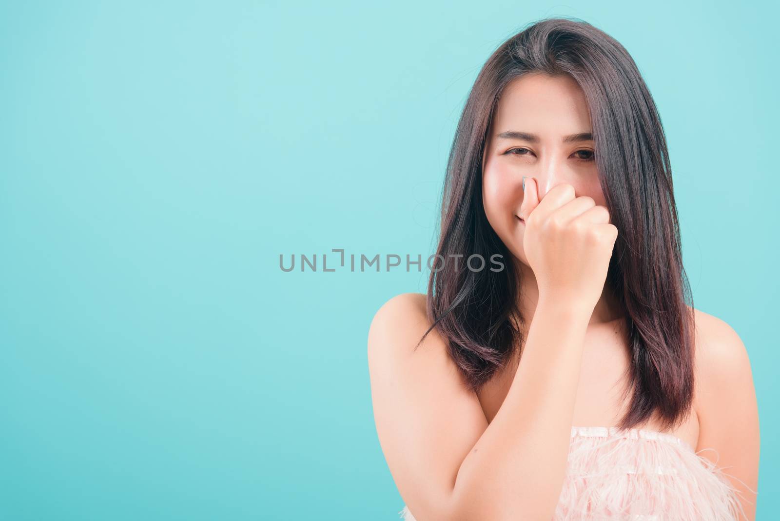 Asian happy portrait beautiful young woman standing smile her very bad smell use hand covers her nose on blue background with copy space for text
