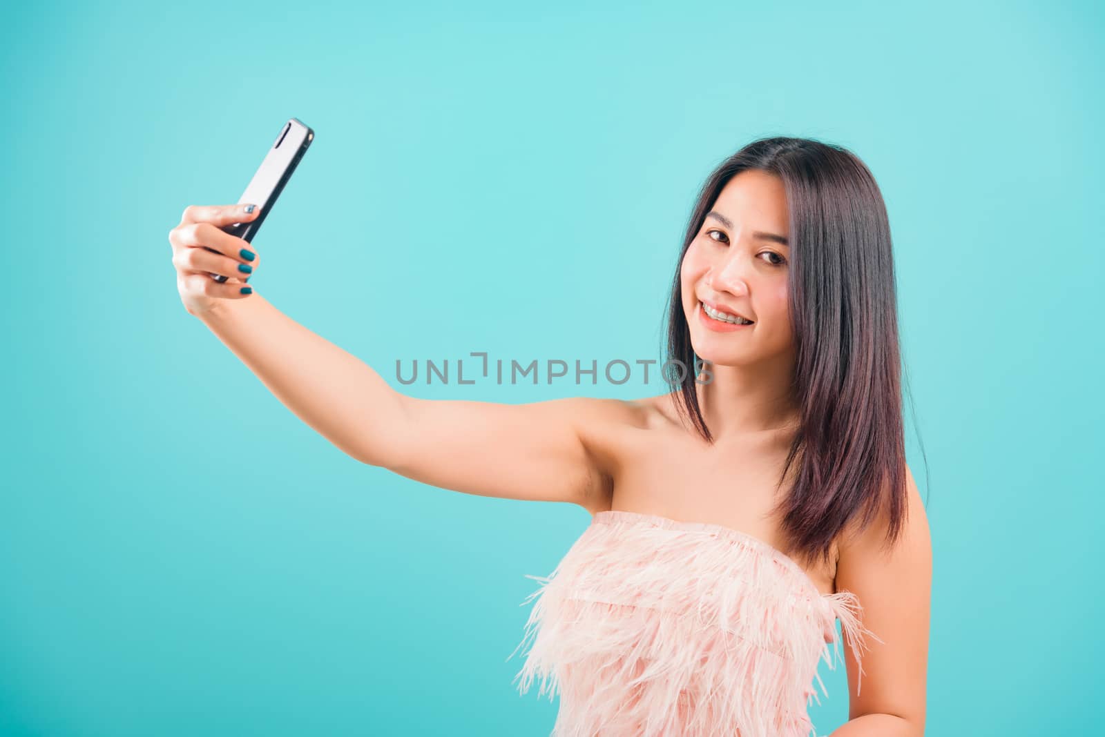 Smiling face portrait asian beautiful woman her standing making selfie photo on smartphone and her looking to camera on blue background