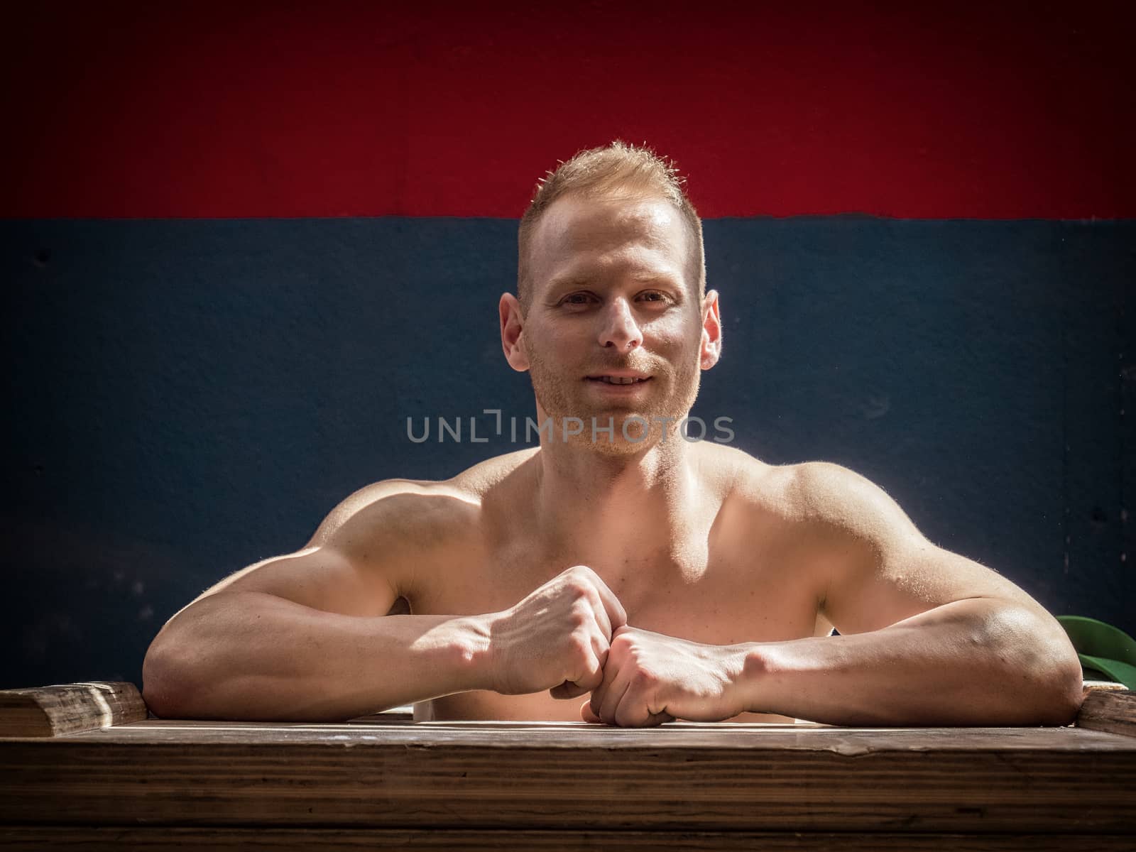Handsome muscular young man standing in gym during workout, looking at camera