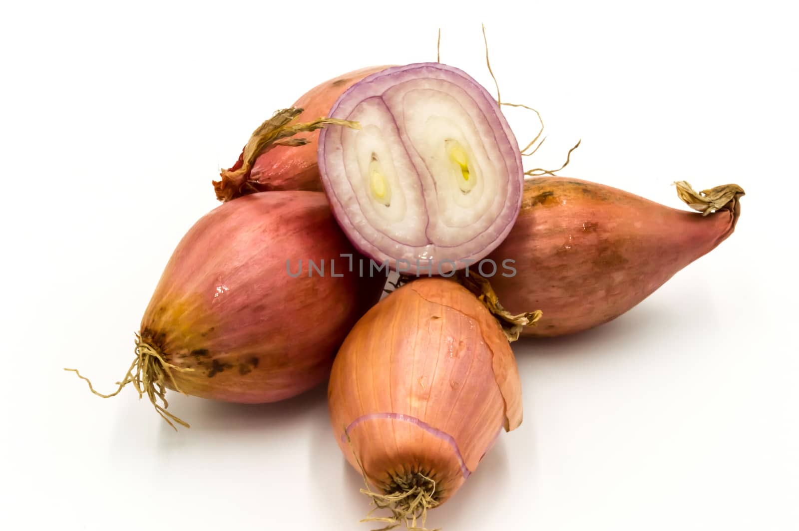 Vegetables: several isolated shallots, one cut in half on a white background
