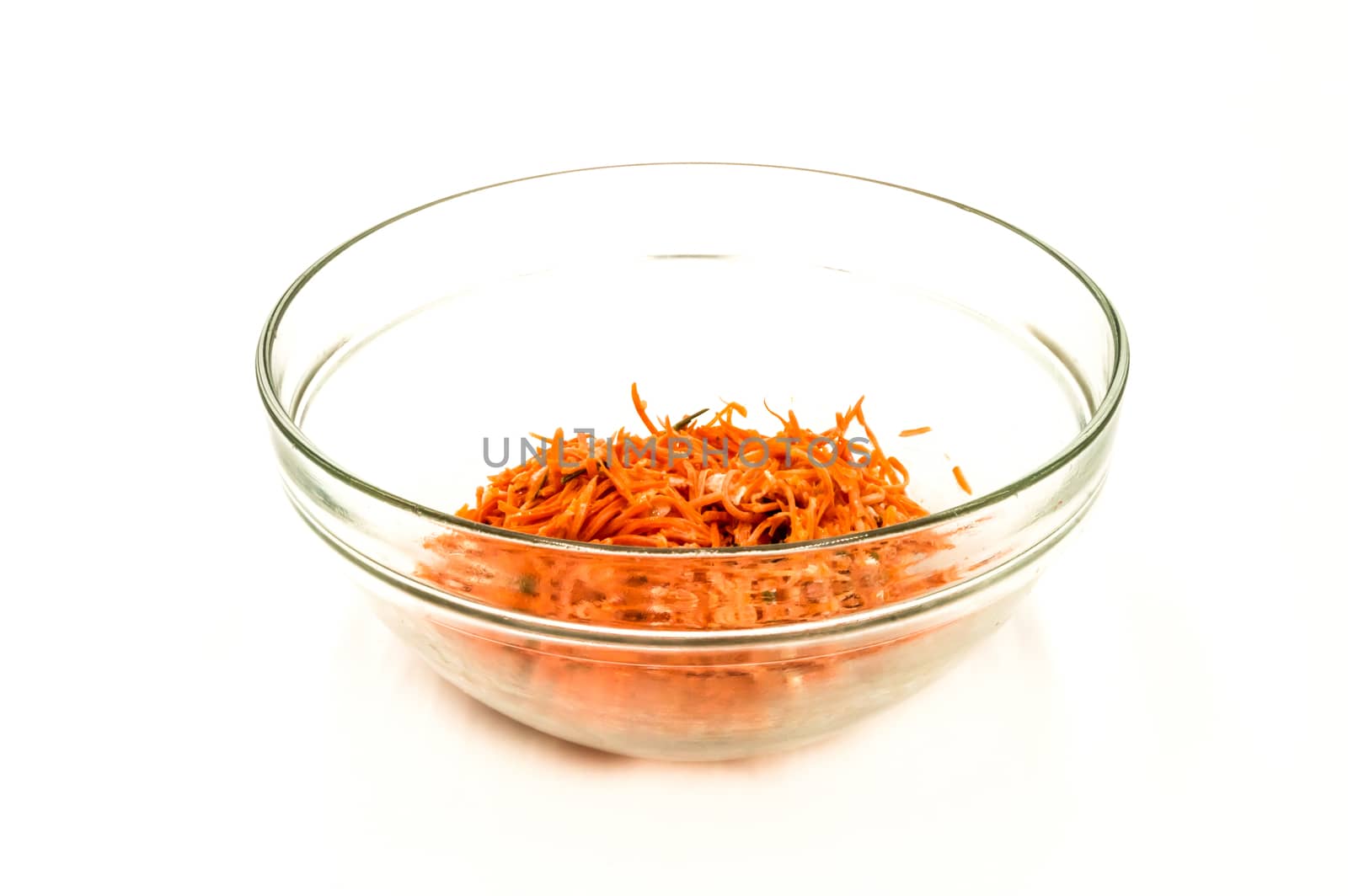 Grated carrot salad in a transparent bowl on a white background