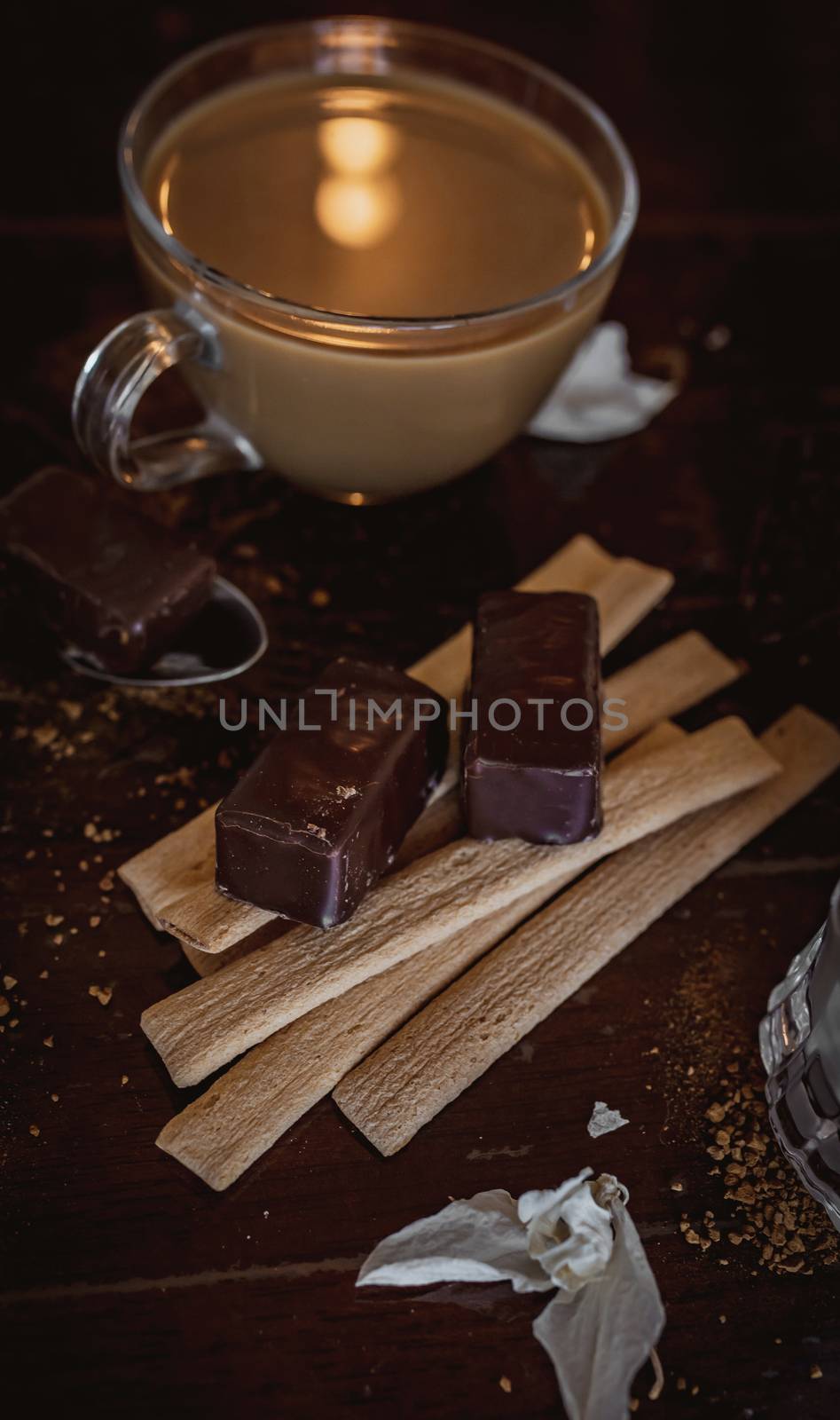 Cup of hot cappuccino with sweets cocoa powder on brown background