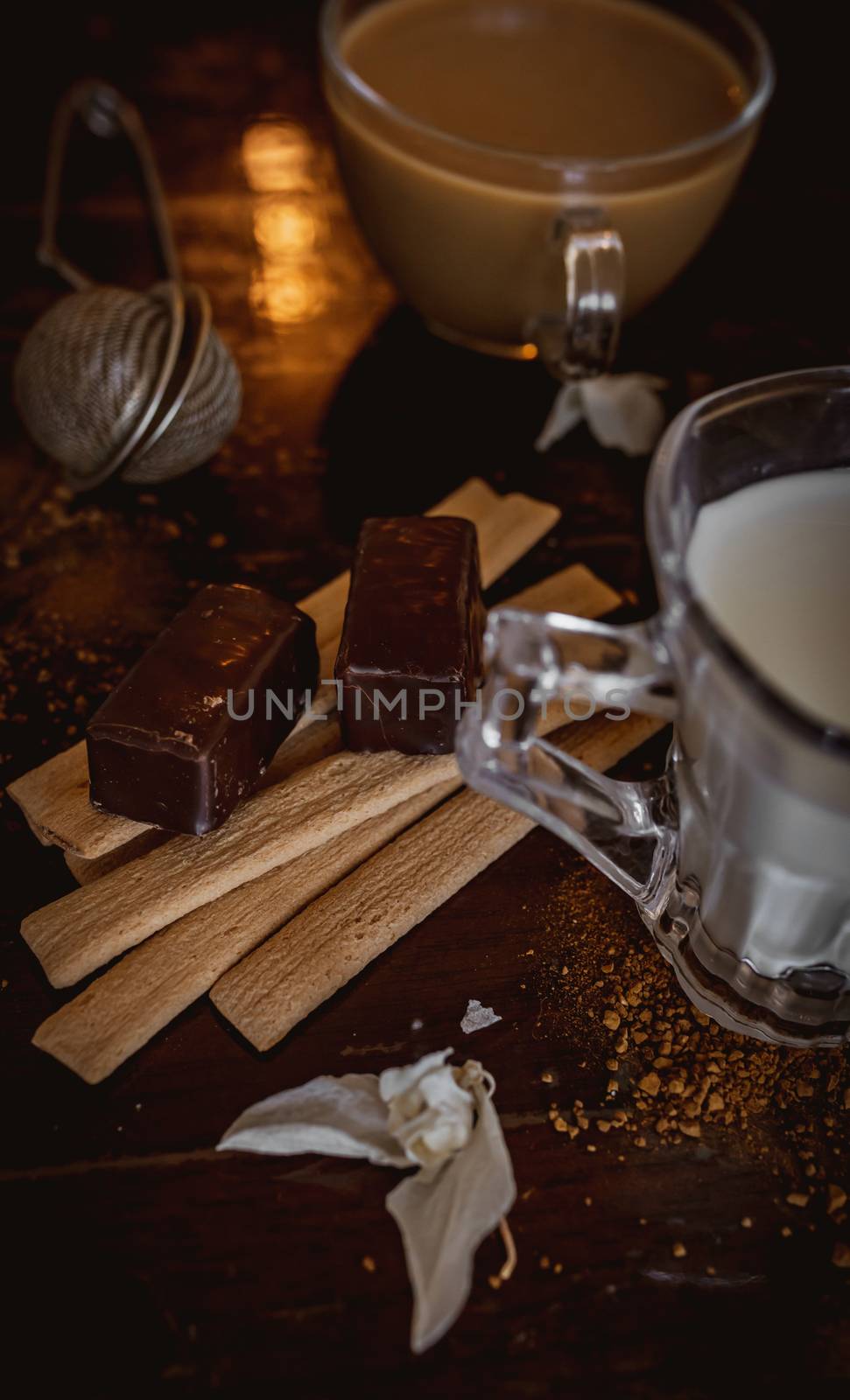 Cup of hot cappuccino with cocoa powder with chocolate sweets on brown background