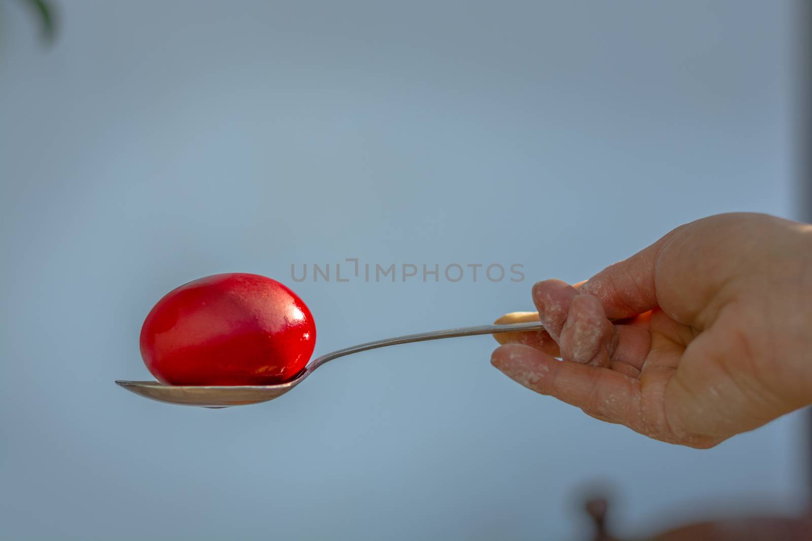 The first red Еaster egg going out of the painт in a metal spoon.