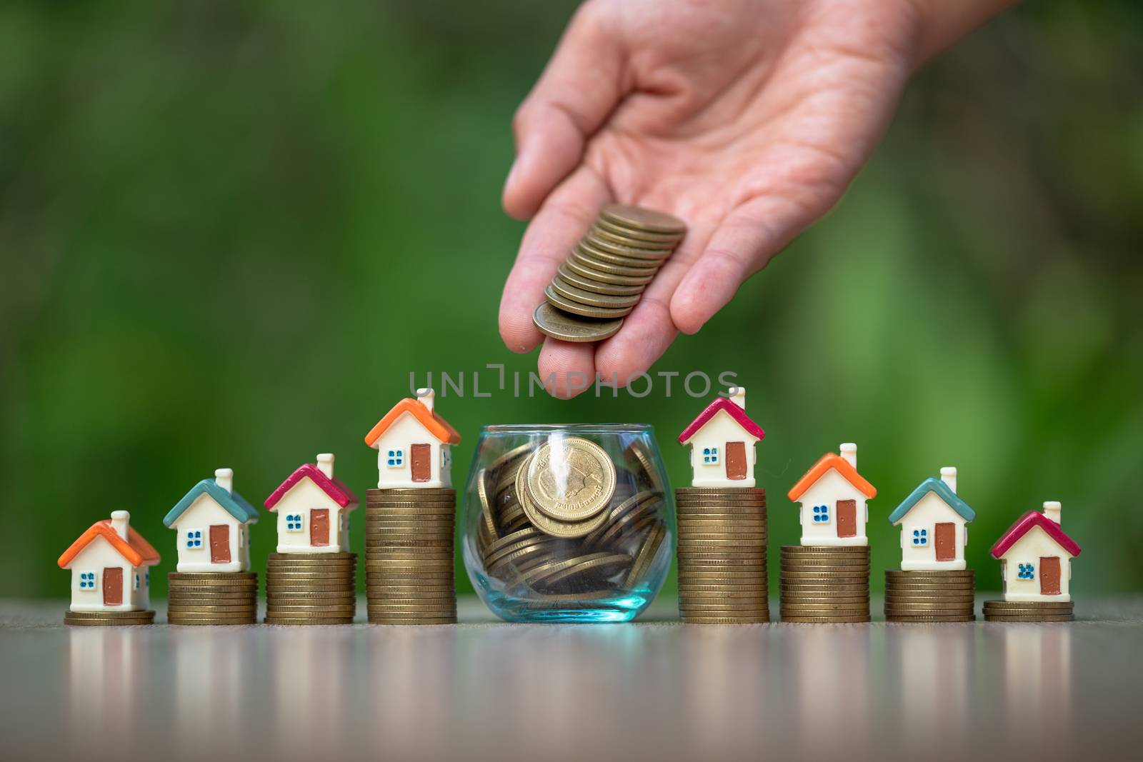 Businessman and accountant is about to put coins in a glass jar. The house is placed on a coin ladder. Saving ideas for buying a home. Business investment. Saving money during retirement.